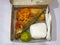 boxed rice filled with fried fish, tempeh flour, coconut milk vegetables and citrus fruits