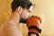 Boxer with concentrated face trains. Man with messy hair on orange texture background. Guy with naked shoulders wears