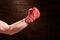 Boxer fist punch with red bandage on a wooden background.