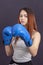 Boxer girl in blue boxing gloves in a gray t-shirt in rack