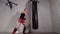 Boxer man training legs and hands blows to combat bag in fighting club. Fighter man training thai box exercise to