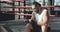 Boxer puts on hand wraps while sitting on the edge of a boxing ring in a boxing gym, camera rotates around