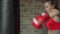 Boxer young female beats pear in a modern gym. Young female athlete in red boxing gloves hits a pear