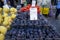 Boxes of delicious dark purple round figs, pears and tomatoes in local fruit market stall background with people