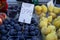 Boxes full of fresh black amber plums with dusty white waxy coating selling next to pears and peaches in local city fruit market