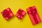 Boxes packed in red paper and tied with ribbon on a yellow background, gifts