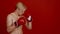 Boxing. Side view portrait of muscular athlete with naked body punching hands in boxing gloves aside at free space
