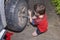Boy 10 years old unscrews the nuts on the wheel of car. Wheel replacement in the yard