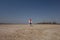 A boy of 10 years old in a white sweatshirt and orange vest plays football on a deserted beach in solitude