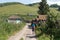 Boy, 12 years old, with a backpack is walking along a dirt road past a wooden fence in the village on a summer sunny day