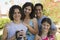 Boy (13-15) holding camcorder standing outdoors with sister (7-9) and parents portrait.