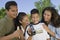 Boy (13-15) looking at camcorder with family outdoors.