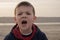 A boy of 4 years in a blue jacket on an empty beach. The child screams and gets nervous