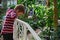 Boy 6-8 years looks down from the bridge in the tropical garden.