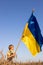 boy 7 years old with a large Ukrainian satin flag on a wheat field against the sky