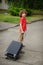 The boy of 8-9 years drags a big suitcase on castors.