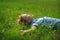 Boy of 8-9 years lies in the field on a green grass.