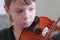Boy of 8 years is playing violin using notes. Face cloe-up.
