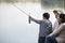 Boy admiring fishing catch with family at lake
