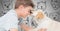 Boy against grey background with friendly dog licking his face and dog faces