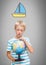 Boy against grey background with world globe and sailing boat