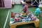 The boy at the age of 3 years plays with the wooden children`s railroad in a children`s corner in entertainment center, the front