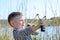 Boy Aiming Sling Shot Outdoors by Lake