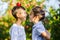 Boy with apple on head tries to keep balance, while her beautiful sister looks at him smiling.