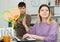 Boy asking mother playing with racquets for tennis, she working at laptop