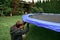 The boy assembles a new trampoline and stretches the springs to jump