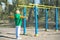 Boy athlete doing pull ups.Active lifestyle. The child performs exercises on uneven bars on the street.