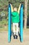 Boy athlete doing pull ups.Active lifestyle. The child performs exercises on uneven bars on the street.