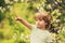 Boy on a background of spring nature. Little hunter. The boy points a finger to something. Beautiful child looks forward