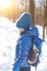 Boy with backpack in woods in winter.