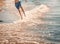 Boy barefoot is jumping on the beach in water