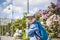 A boy in a baseball cap rides a scooter along a lilac alley .  Against the background of lilac bushes. Interactions. Selective