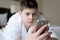 Boy in bathrobe writes sms on phone in hotel room