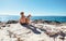 Boy with beagle dog sitting together on rocky sea coast at sunny