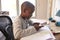 Boy In Bedroom Using Digital Tablet To Do Homework