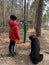 Boy with a big dog for a walk in the woods. A teenager walks with a black dog in the park. Cane Corso on a leash
