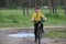 A boy on a bike rides a puddle and laughs.