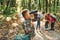 Boy with binoculars standing in front of his friends. Kids in green forest at summer daytime together