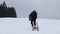 Boy in black winter clothes pulls a sledge to the top of the slope. Enjoying young age. Winter fun. Fooling around in the snow. Fu