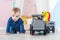 Boy blond in a blue sweater crawls on a wooden floor. One year old baby playing with wooden toys.  train made of wood, with girafe