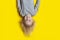 Boy with blond hair on bright yellow background. Portrait of cheerful boy, upside down