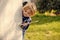 Boy with blond hair with stick smile at wall corner