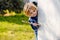 Boy with blond hair with stick smile at wall corner