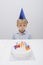 Boy blowing candles on birthday cake at table in house