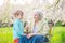 Boy blowing dandelion seeds while his great grandmother is holding a flower