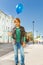 Boy with blue flying balloon standing on street